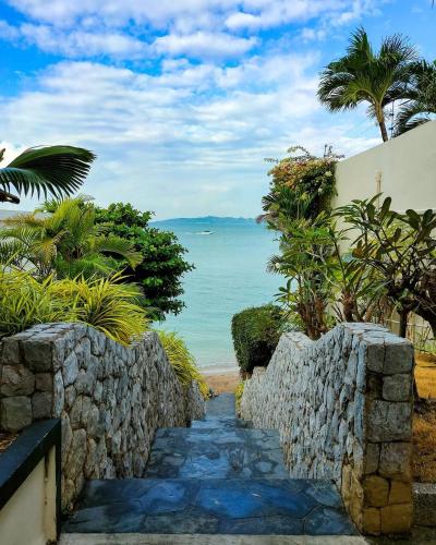 a stone path leading to the beach with a stone wall at Majestic Residence Pool Villa Private Beach in Pattaya South