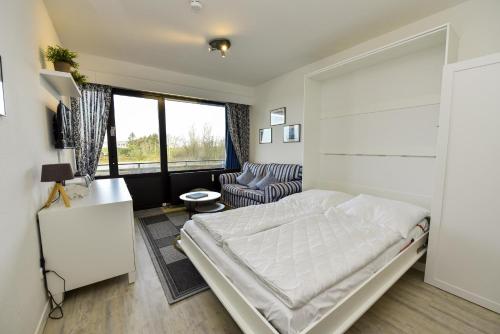 DöseにあるHaus "Jan am Strand" Appartement JAN103のベッドと椅子のある白い寝室
