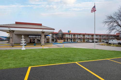 a building with a flag in front of a parking lot at Days Inn by Wyndham Perrysburg Toledo in Perrysburg