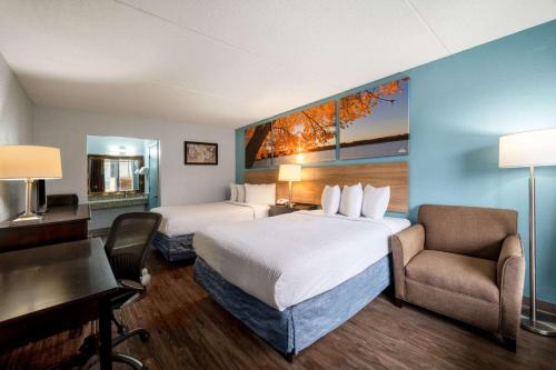 a hotel room with two beds and a desk at Days Inn by Wyndham Perrysburg Toledo in Perrysburg