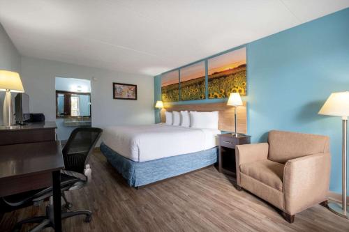 a hotel room with a bed and a desk and a chair at Days Inn by Wyndham Perrysburg Toledo in Perrysburg