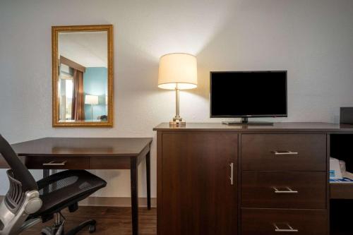 a room with a desk and a television and a lamp at Days Inn by Wyndham Perrysburg Toledo in Perrysburg