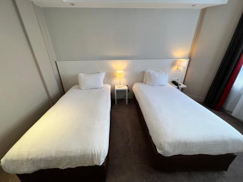two beds in a small room with white sheets at Holiday Inn Paris-Auteuil by IHG in Paris