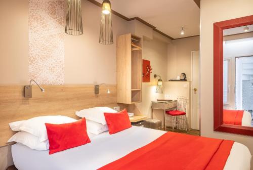 una camera da letto con un grande letto bianco con cuscini rossi di Hotel Eiffel Segur a Parigi