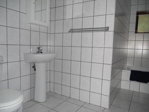 een wit betegelde badkamer met een toilet en een wastafel bij Shore Breakers in Shelly Beach