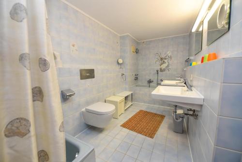 ein blau gefliestes Badezimmer mit Toilette und Waschbecken in der Unterkunft Haus "Jan am Strand" Appartement JAN504 in Döse