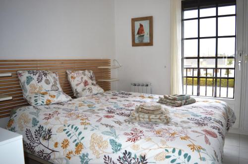 sypialnia z łóżkiem z kołdrą kwiatową w obiekcie Triplex avec jardinet - wifi - à 400m de la plage w mieście Courseulles-sur-Mer