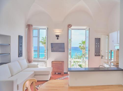 a living room with a white couch and a view of the ocean at Medusa Apartment - Piazza 2 in Finale Ligure