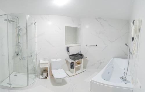 a white bathroom with a shower and a toilet and a sink at SOMARA in Găineşti