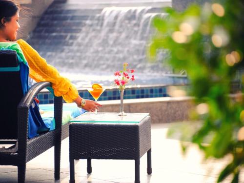 a woman sitting at a table with a vase of flowers at Welcomhotel By ITC Hotels, Guntur in Guntūr
