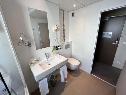 a white bathroom with a sink and a toilet at Holiday Inn Paris-Auteuil by IHG in Paris