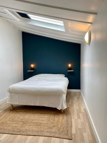 - une chambre avec un lit blanc et un mur bleu dans l'établissement magnifiques appartements au coeur de Bordeaux, à Bordeaux