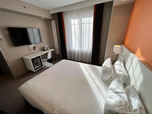 a hotel room with a bed and a television at Holiday Inn Paris-Auteuil by IHG in Paris