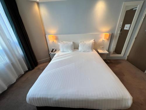 a large white bed with two pillows in a room at Holiday Inn Paris-Auteuil by IHG in Paris