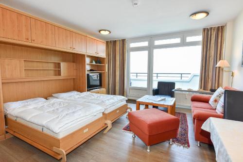 a bedroom with a bed and a couch and a chair at Haus "Panorama" Appartement PAN027 in Duhnen