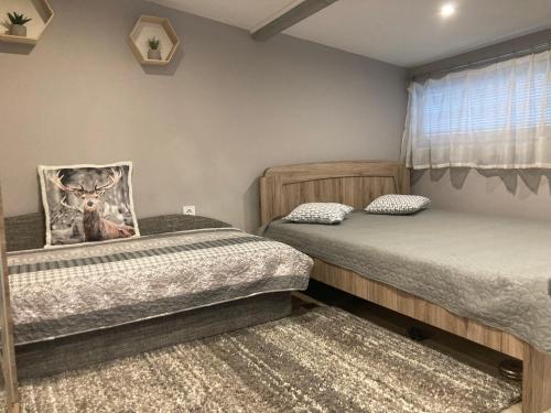 a bedroom with two beds and a picture of a deer at Gólya-Tó Vendégház in Vajdácska
