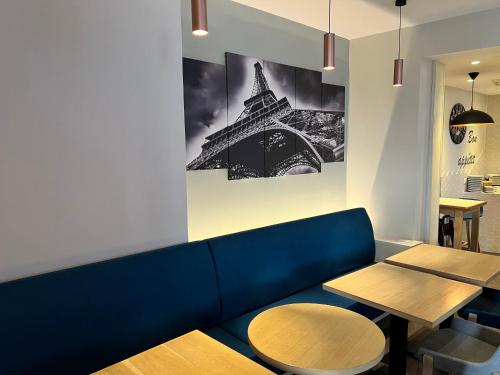 a blue couch with two tables and a picture of the eiffel tower at Holiday Inn Paris-Auteuil by IHG in Paris