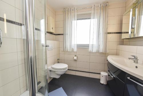 a bathroom with a toilet and a sink and a shower at Haus "Panorama" Appartement PAN063 in Duhnen