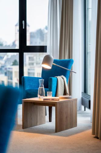 a living room with a blue couch and a table with a lamp at KONCEPT HOTEL Benedikt in Siegburg