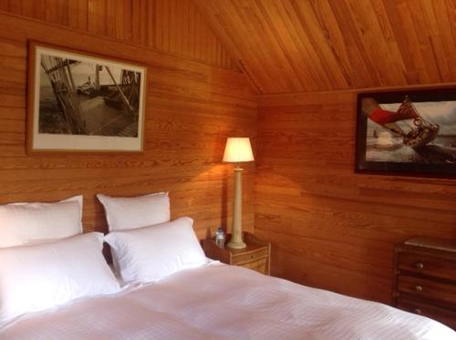1 dormitorio con 1 cama blanca y paredes de madera en Domaine de Thyllères,Chalets Voilier, en Beaufour