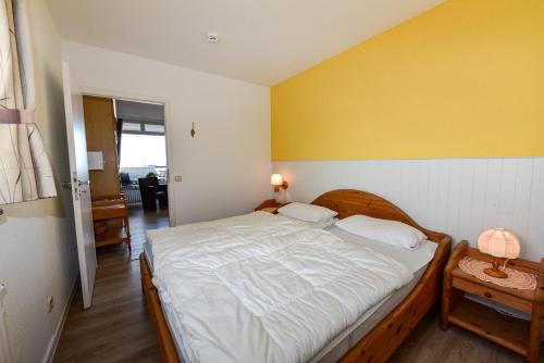 a bedroom with a bed and a yellow wall at Haus "Panorama" Appartement PAN096 in Duhnen