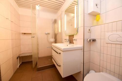 a white bathroom with a sink and a toilet at Haus "Panorama" Appartement PAN096 in Duhnen