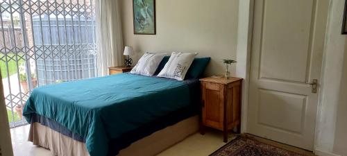 sypialnia z łóżkiem z niebieską pościelą i oknem w obiekcie Dollery House w mieście Port Alfred