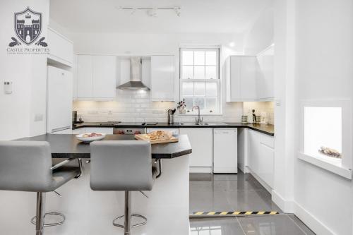 a white kitchen with a table and chairs at Castle Properties: The Sovereign 5 Bed Town House in Windsor