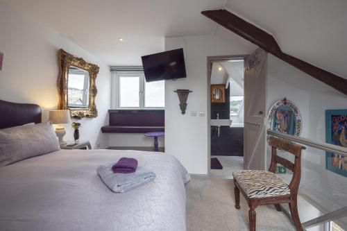 a bedroom with a bed and a chair and a mirror at Cornerways Guest House in St Ives