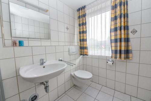 La salle de bains est pourvue d'un lavabo, de toilettes et d'un miroir. dans l'établissement Haus "Seeland 2" Appartement SEE209, à Duhnen