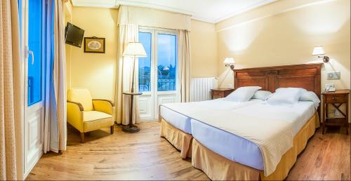 a bedroom with a bed and a chair and a window at Silken Spa La Hacienda De Don Juan in Llanes