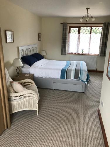 a bedroom with a large bed and a chair at Meadowview in Cullompton