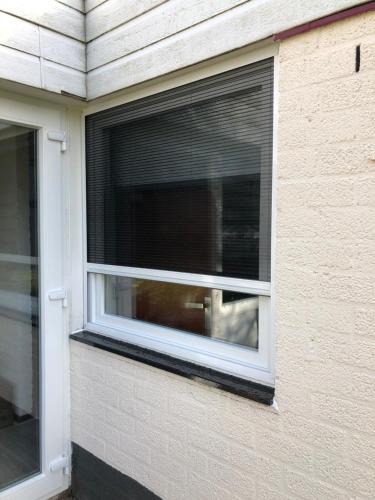 a window with blinds on the side of a building at Vakantiebungalow nr 7 in het Heuvelland in Simpelveld