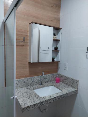 ein Badezimmer mit Waschbecken und Spiegel in der Unterkunft Ótimo apartamento sobreloja com wifi e estacionamento incluso in Maringá