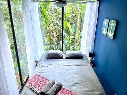 una cama en una habitación con una ventana grande en Villa JOEYSHE- New Luxury Villa with Pool & AC, en Puerto Viejo