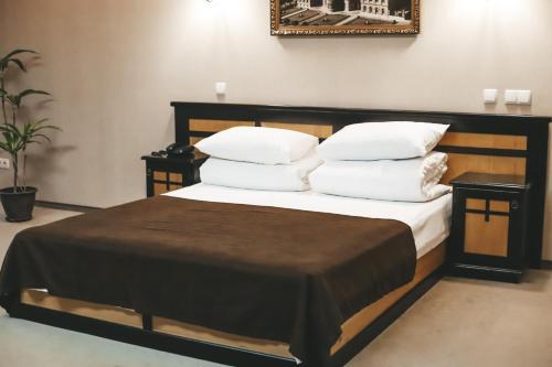 a bedroom with a bed with white sheets and pillows at Georg Palace Hotel in Chernivtsi