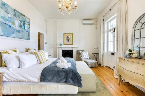 a bedroom with a large bed and a chandelier at Backup-Powered Victorian House at GreenPoint Park in Cape Town