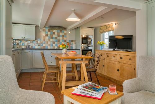 a kitchen with a table and chairs and a television at Finest Retreats - The West Wing at Gypsy Hall in Dullingham