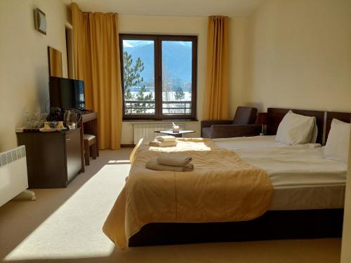 um quarto com uma cama grande e uma janela grande em The View Apartment, Terra Complex neighbour building em Bansko