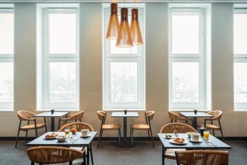 a dining room with tables and chairs and windows at ibis Paris porte de Bercy in Charenton-le-Pont