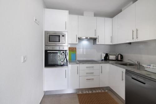 a kitchen with white appliances and white cabinets at Adelino Guest House in Olhão