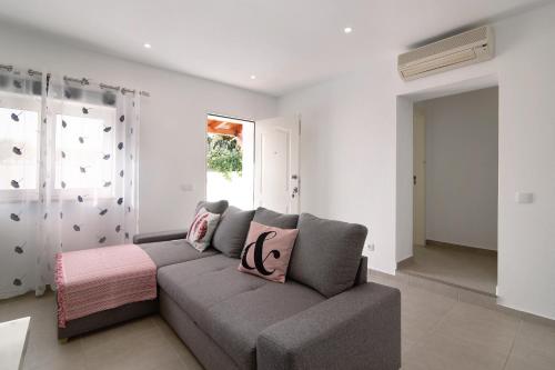 a living room with a gray couch and a window at Adelino Guest House in Olhão