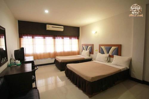 Una habitación de hotel con dos camas y un escritorio. en ไทยโฮเต็ล, en Buriram