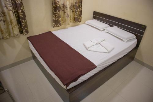 - un lit avec des draps blancs et des serviettes dans l'établissement Shri Vasant Lodge, à Hubli