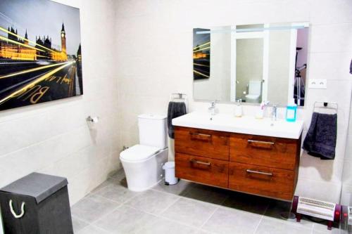 a bathroom with a sink and a toilet and a painting at Spa, Sierra y sol in Cortes de la Frontera
