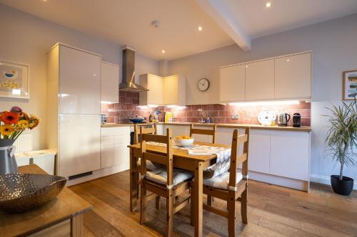 una cocina con mesa y sillas y una cocina con armarios blancos. en Silverdale Mews en Eastbourne