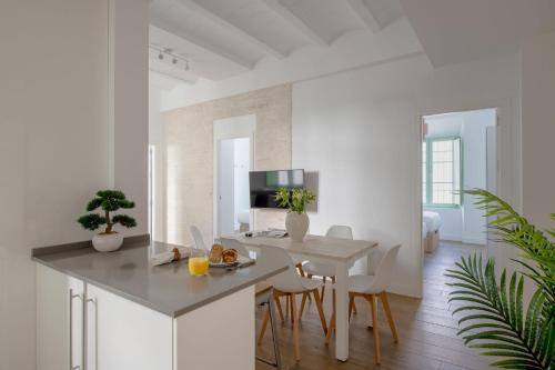 a white kitchen with a table and a dining room at Hommyhome Teodosio in Seville