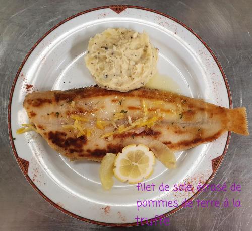 a plate with a piece of fish and mashed potatoes at Hôtel Restaurant La Paix La Robe et le Palais in Forges-les-Eaux