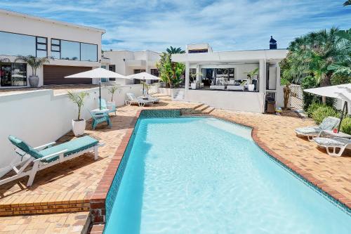a swimming pool with chairs and a house at The Model House in Cape Town