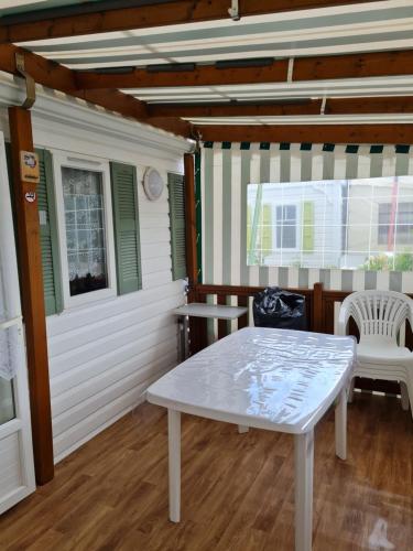 - une table et des chaises blanches sur une terrasse couverte dans l'établissement Mobil home sur camping 4 étoiles CAP SOLEIL St Denis d'Oléron, à La Bétaudière